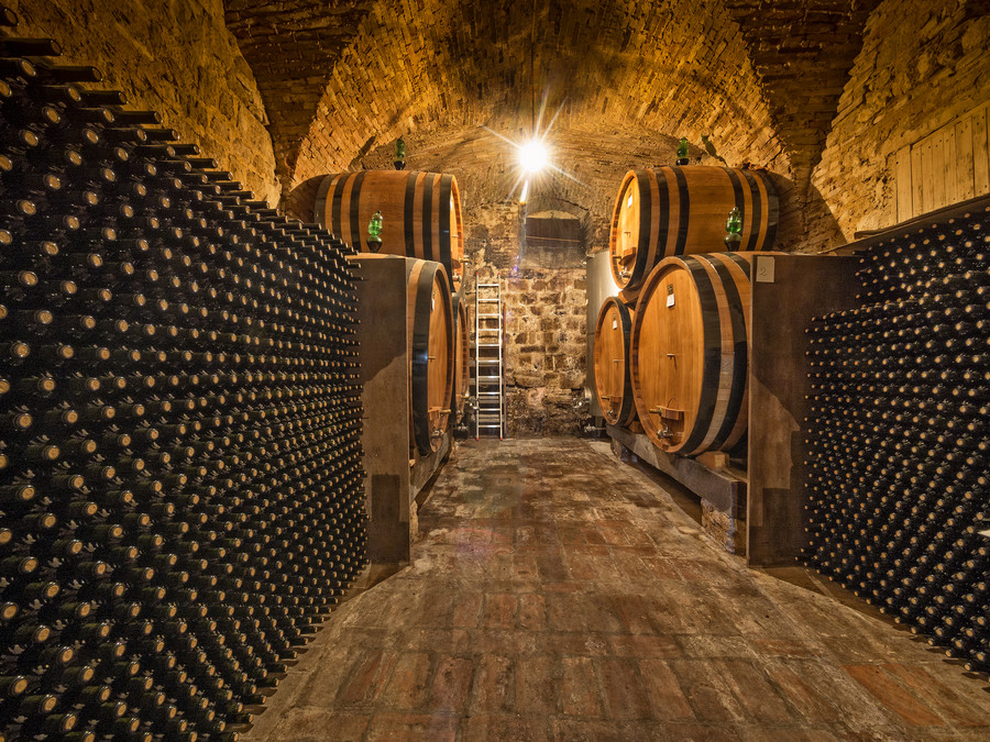 Photograph wine bottles and oak barrels in background by Christian Delbert on 500px