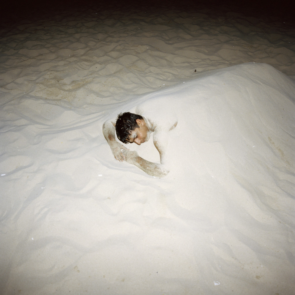 U.A.E. Dubai. A man burried in the sand on Jumeirah Beach. 2013