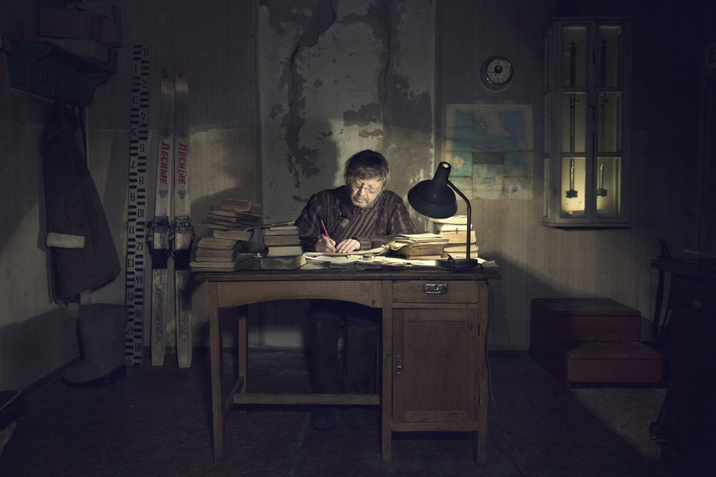 Slava in his office writes down the collected data in the journal after his observations on the meteorological field outside.