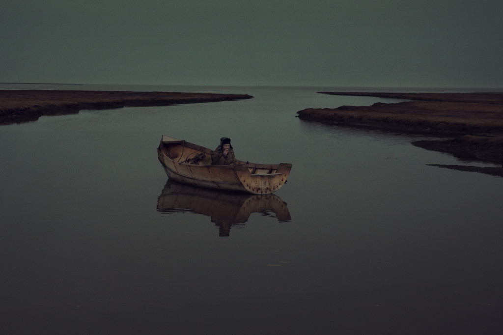 Slava in his handmade boat on the bay of Barents Sea near meteorological station.