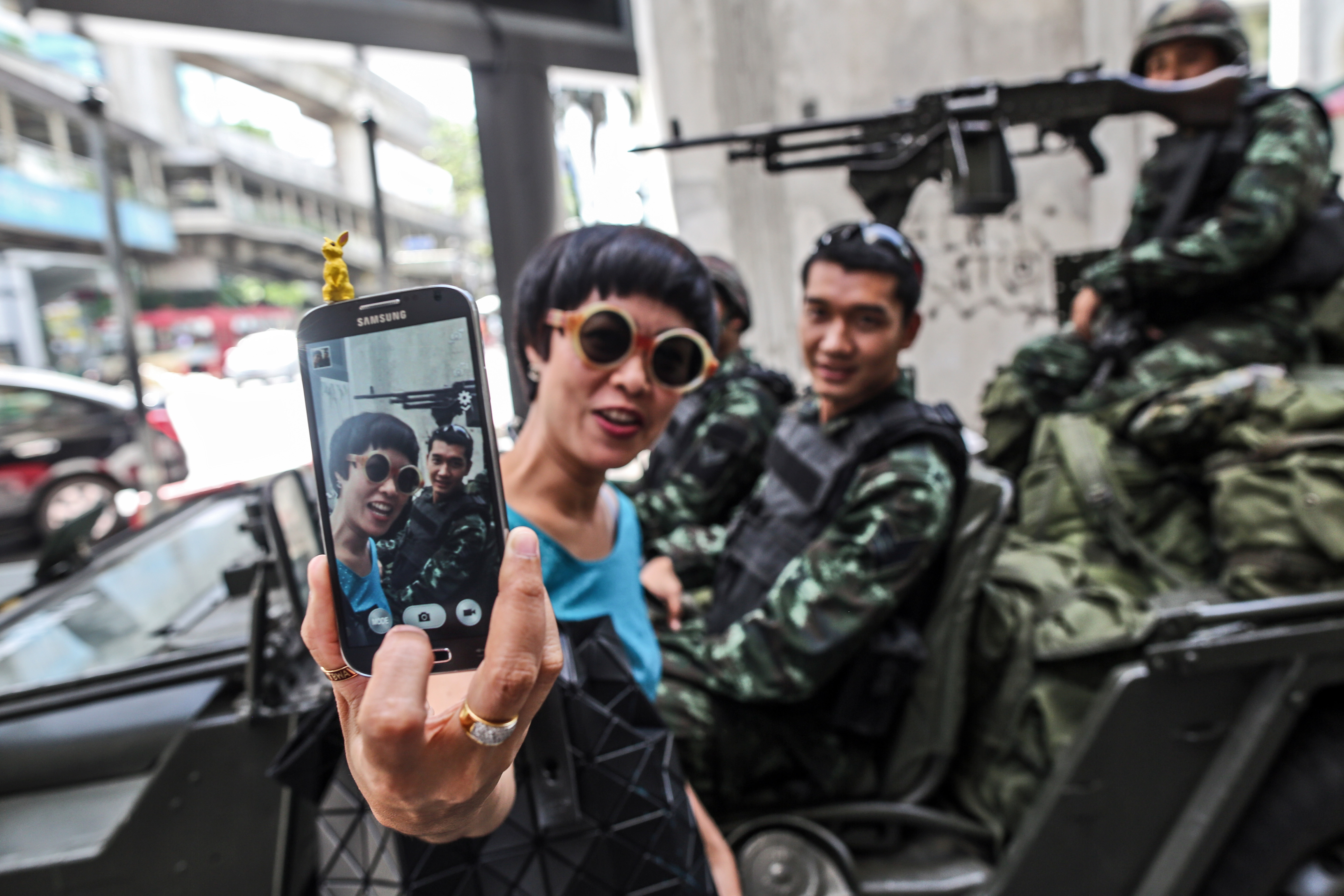 A women takes a selfie picture with Royal Thai Army soldiers stationed at the Ratchaprasong intersection, as martial law is imposed, in Bangkok, Thailand, on Tuesday, May 20, 2014.